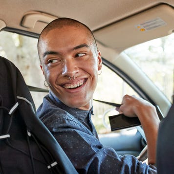 Person in driver's seat of car looking over their shoulder while fastening seatbelt