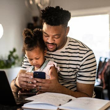 Dad works on computer with daughter on his lap