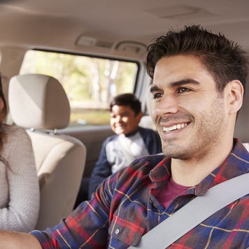A man drives his family on a trip in their van; everyone is smiling and having a great time!