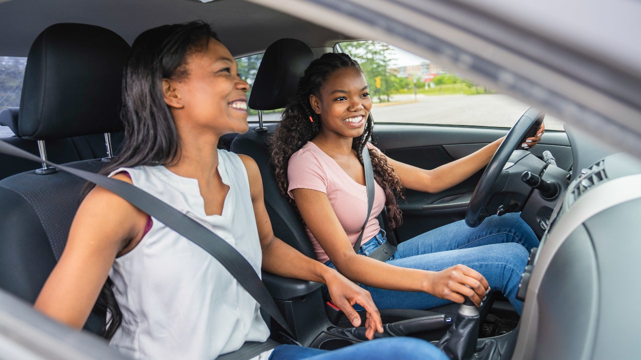 Daughter and mother in car, daughter driving, both smiling