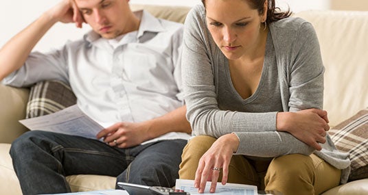 Couple working on finances on couch © CandyBox Images/Shutterstock.com