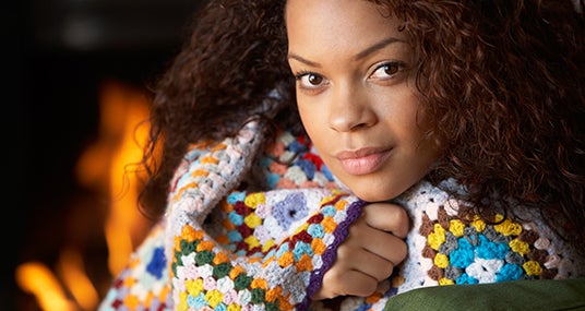 Woman keeping warn with a blanket and fire © oliveromg/Shutterstock.com
