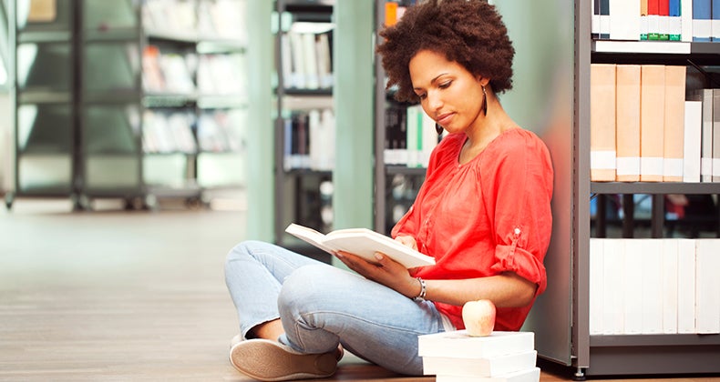 Female college student reading in library