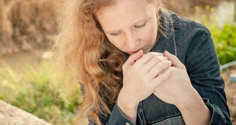Sad woman sitting outside on a cement wall © altanaka/Shutterstock.com