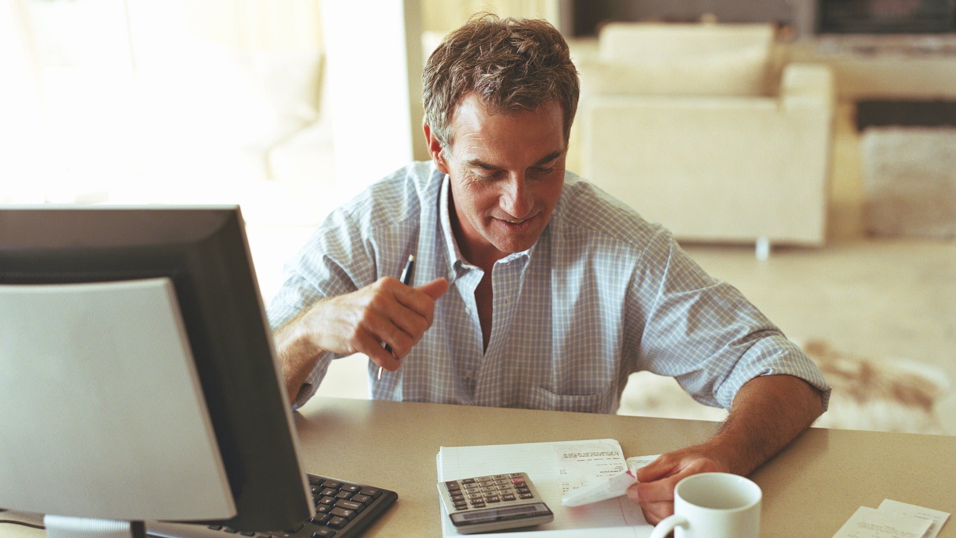 Mature man sitting at desk checking receipts