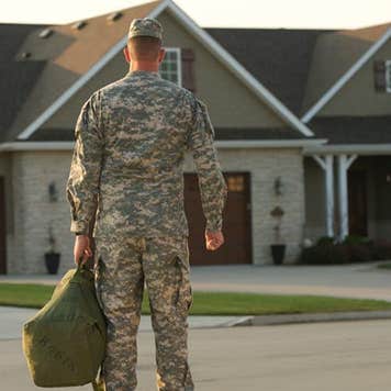 Military man wearing fatigues standing outside of his home