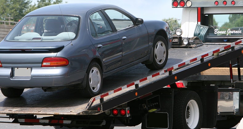 Car being lifted onto tow truck bed 