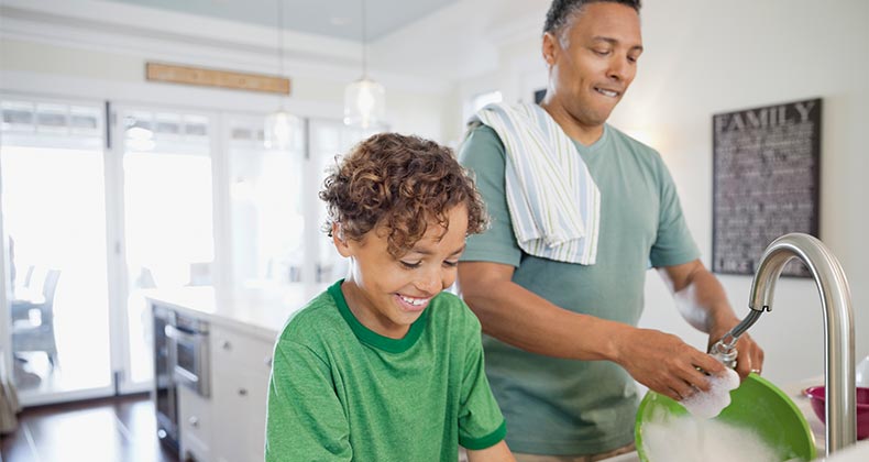 Dad and son doing dishes in kitchen | Hero Images/Getty Images