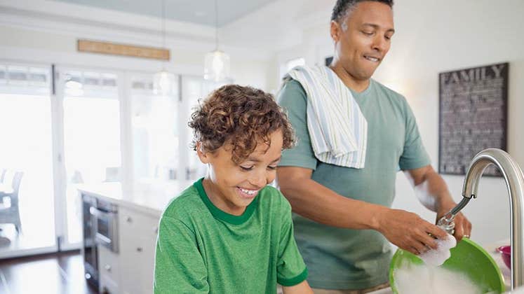 Dad and son doing dishes in kitchen | Hero Images/Getty Images