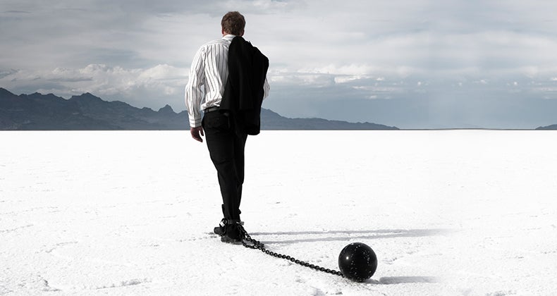Disappointed businessman dragging ball and chain © iStock