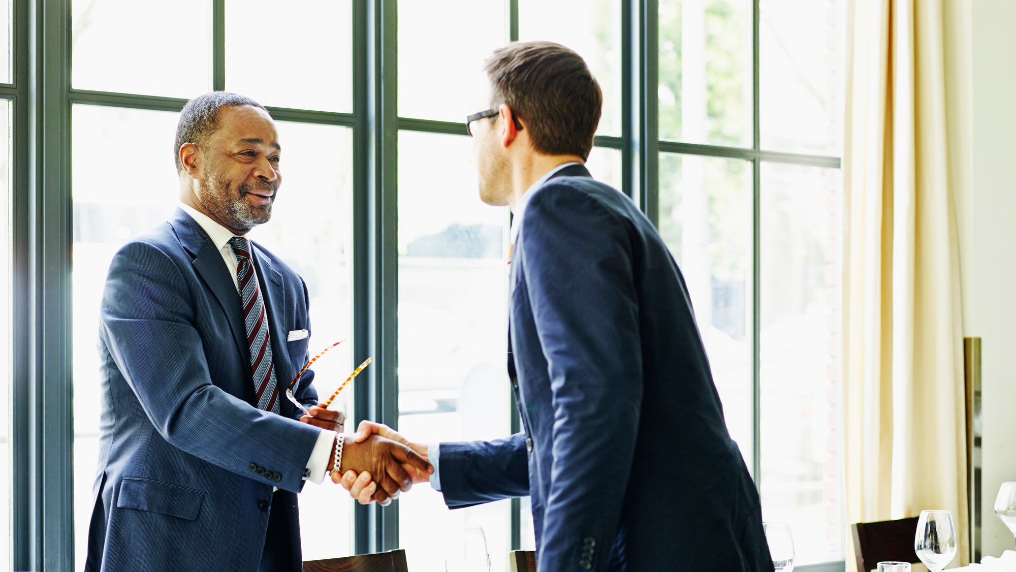 Two businessmen shaking hands at lunch meeting