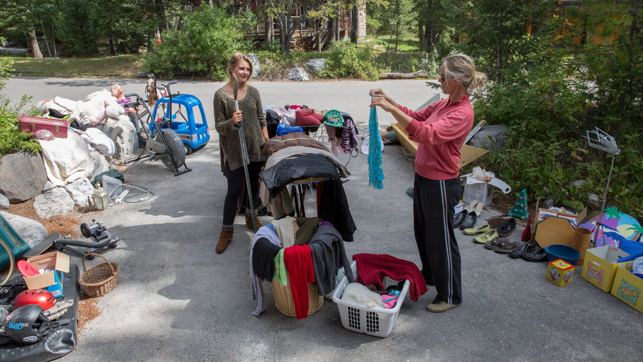 Women look over belongings at garage sale,driveway