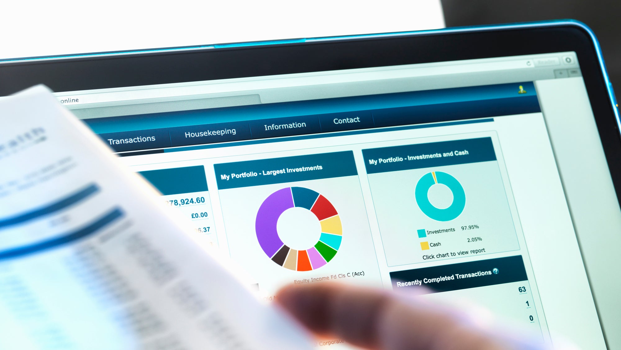 Investor checking performance of financial portfolio online whilst reviewing investment statement