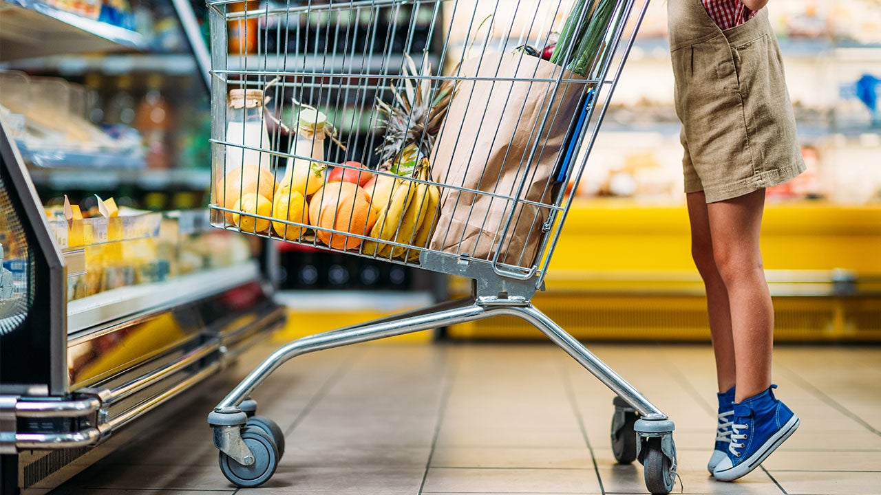 Boy on tiptoes with shopping cart