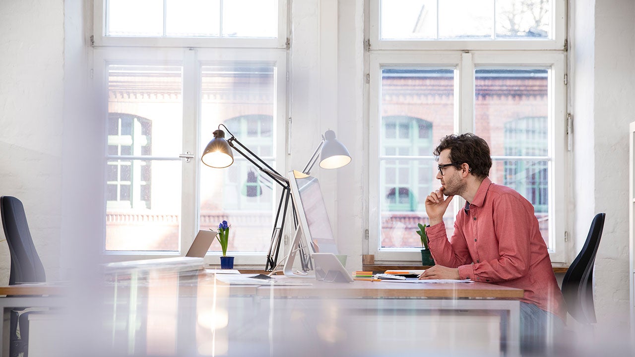 Man sits at his desk looking at computer