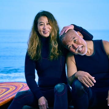 An older surfer couple hug at the beach