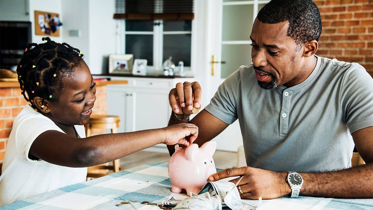 Father and daughter saving money in piggy bank