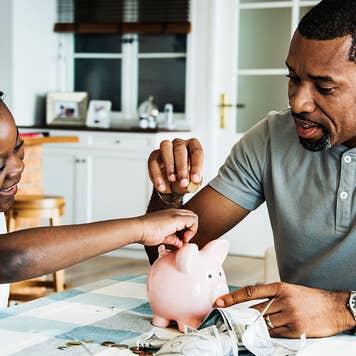 Father and daughter saving money in piggy bank