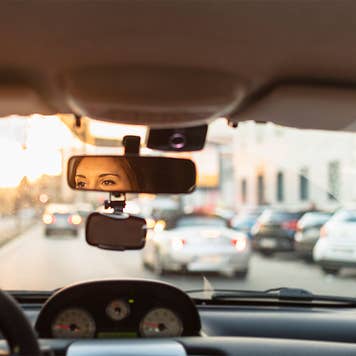 Woman looking in rear view mirror