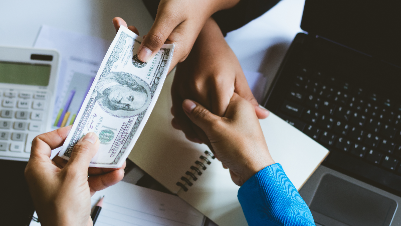 hand shaking, exchanging money across desk