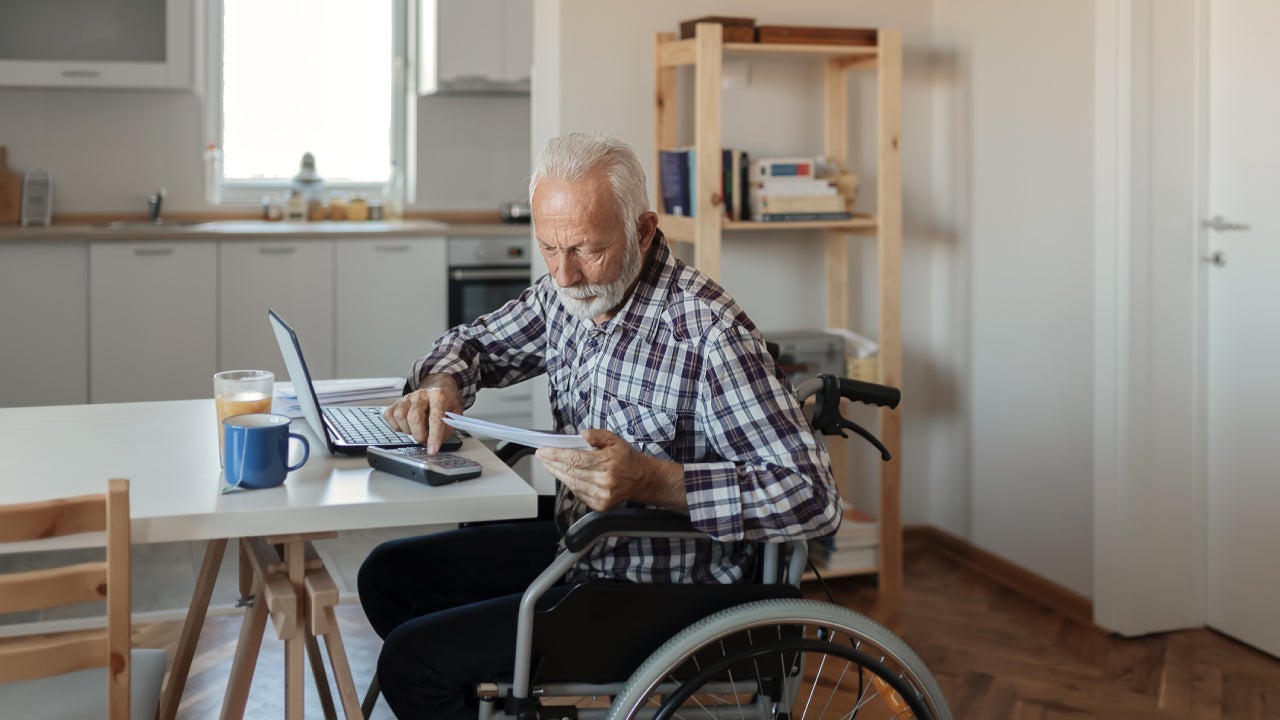 Disabled Senior Man in a Wheelchair Working From Home