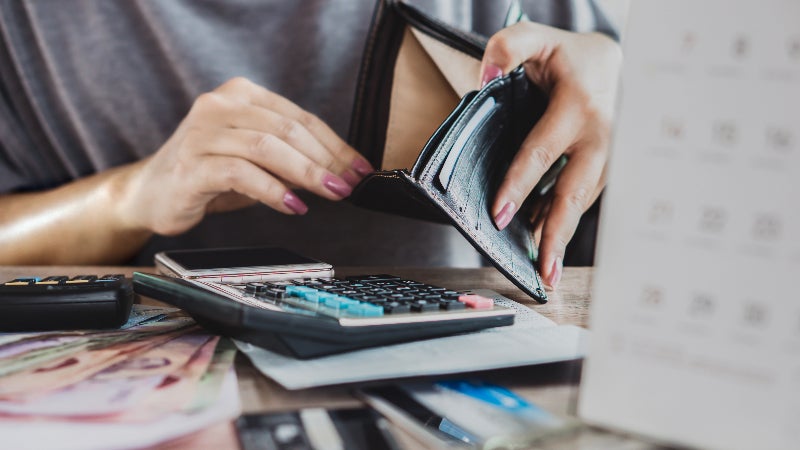 woman at desk with open wallet, calculator and papers