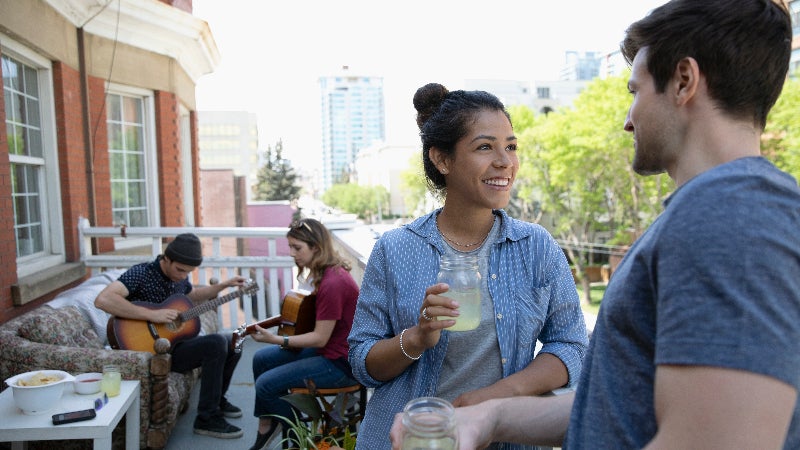 Millennial friends hanging out and playing guitars on apartment balcony