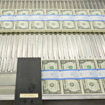 Stacks of dollars bills moving through a machine at the U.S. Bureau of Engraving and Printing