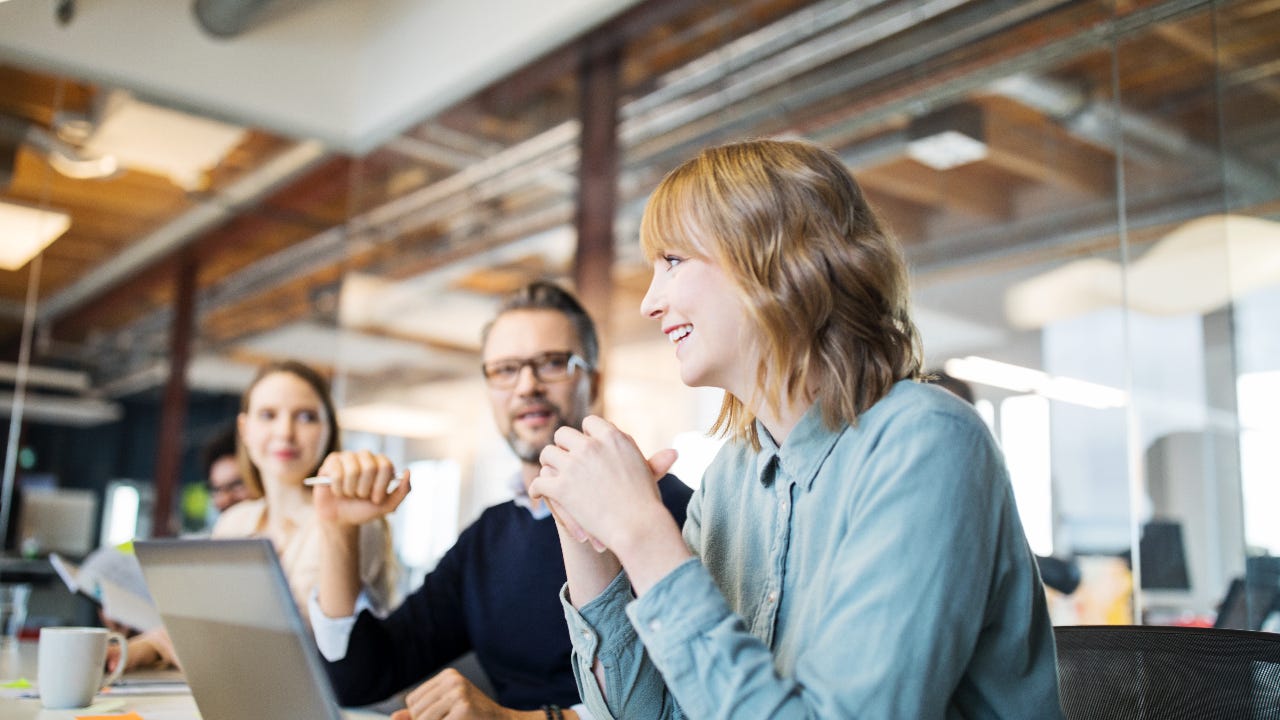 A woman laughs with colleagues at an office table