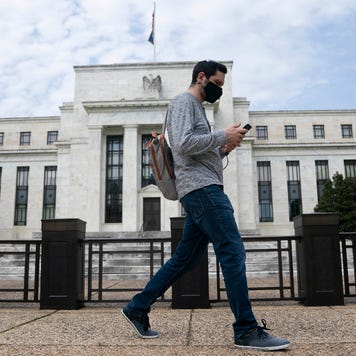 A man wearing a mask walks past the U.S. Federal Reserve building in Washington D.C.
