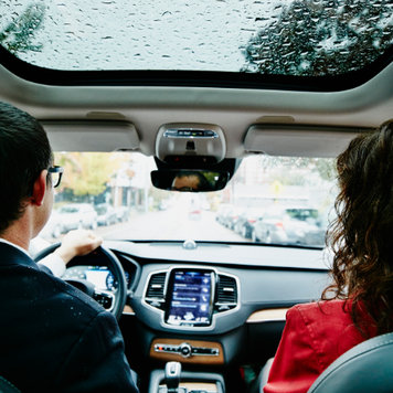 man and woman driving in car on rainy day