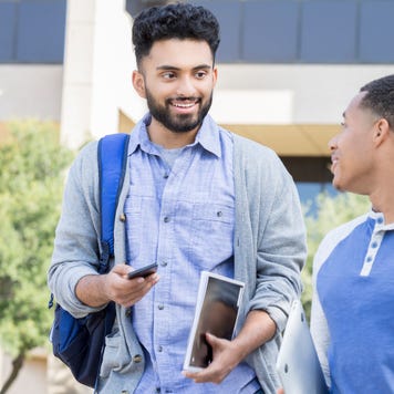 Male friends walk on a college campus.