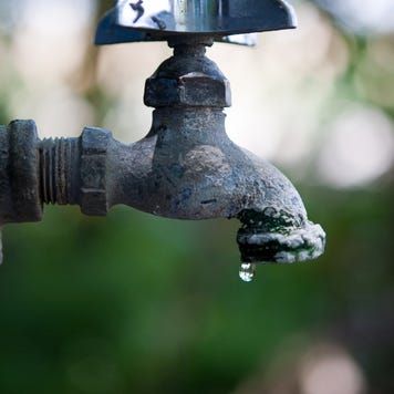 A water faucet leaks a drop of water