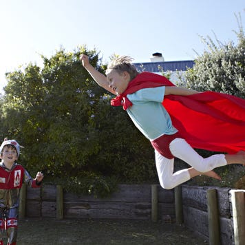 Two boys play superheroes out in the backyard.