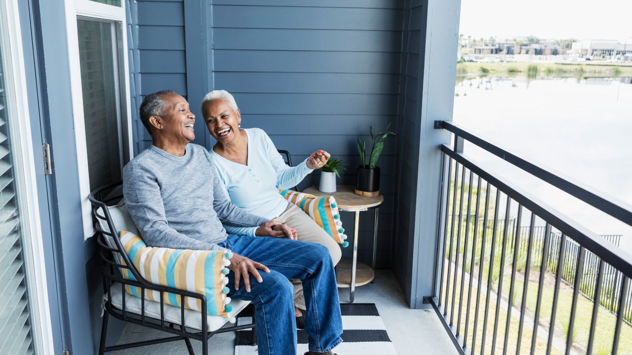 Two seniors enjoy sitting outside their home