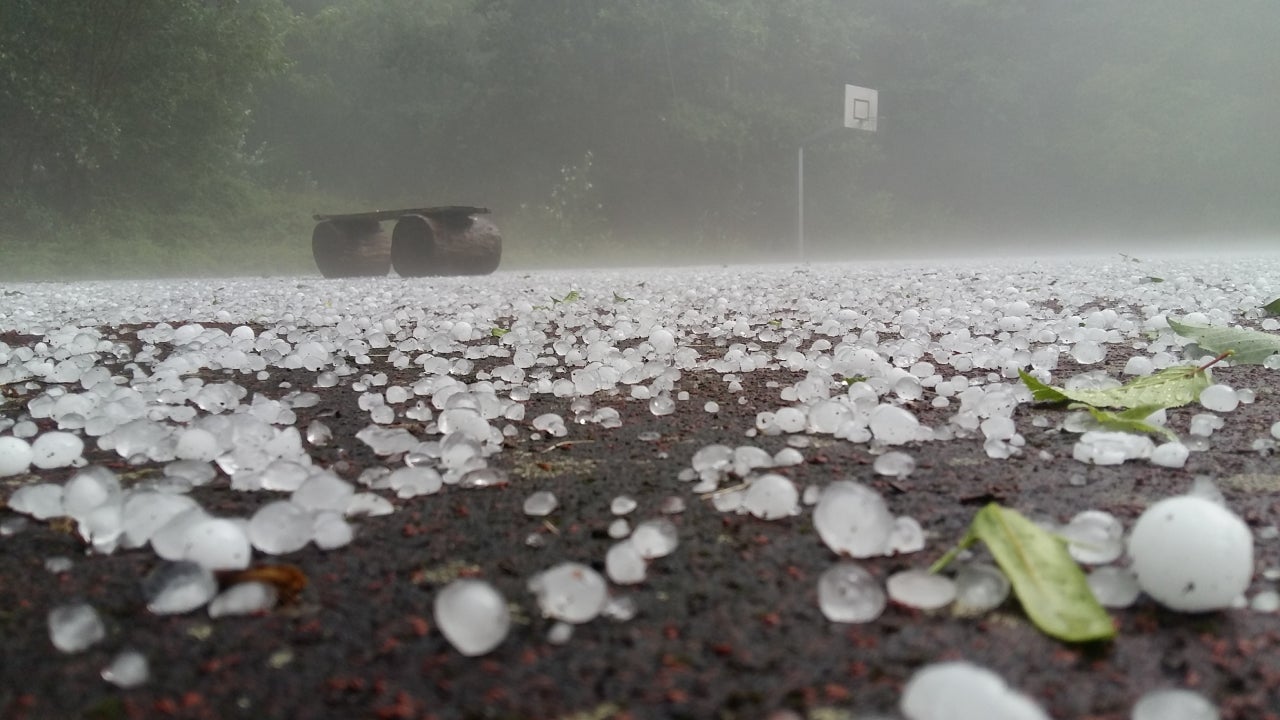 Close-up shot of golf-ball-sized hail stones on the ground.