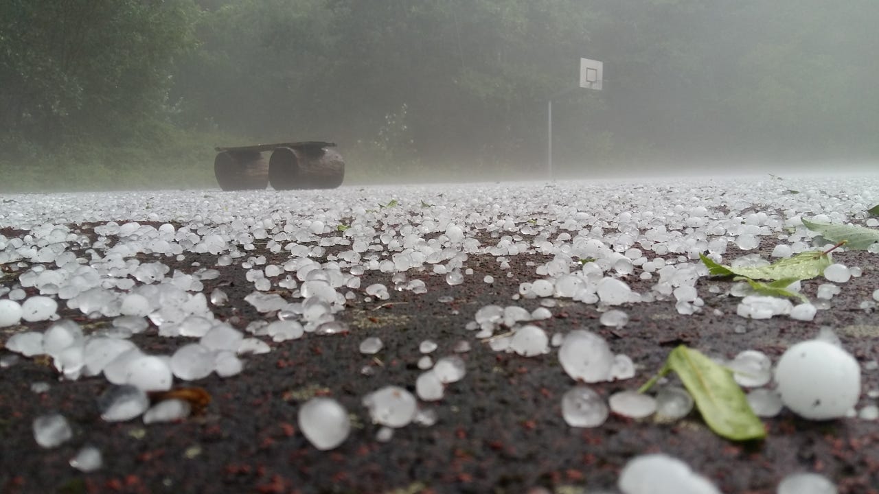 Close-up shot of golf-ball-sized hail stones on the ground.