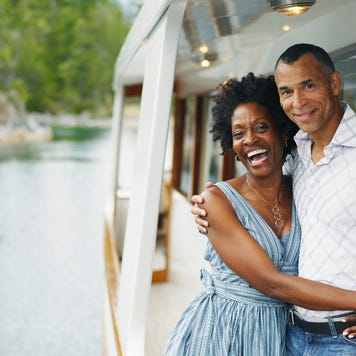 An older Black couple hangs off a boat