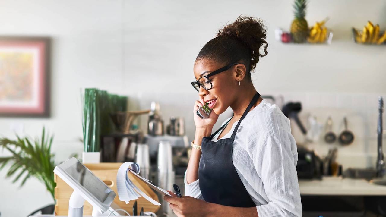friendly waitress taking order on phone at restaurant and writing on notepad
