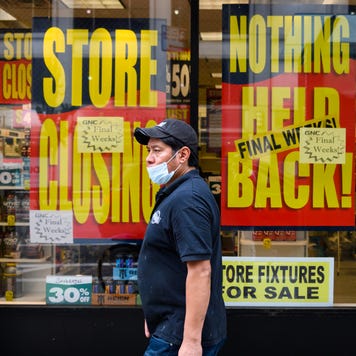 A person wears a protective face mask outside a GNC store.