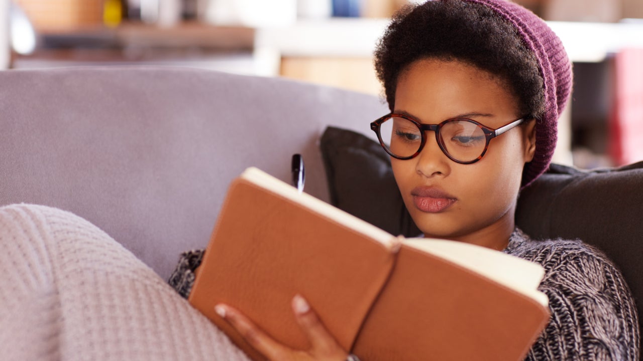Young woman reading a book while relaxing on her sofa