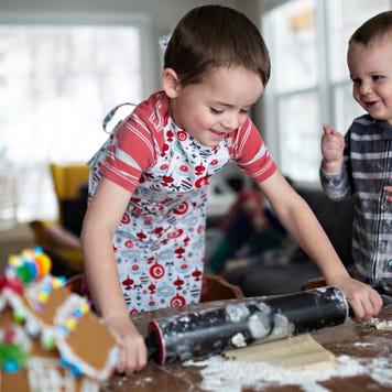 Two young brothers bake cookies together.