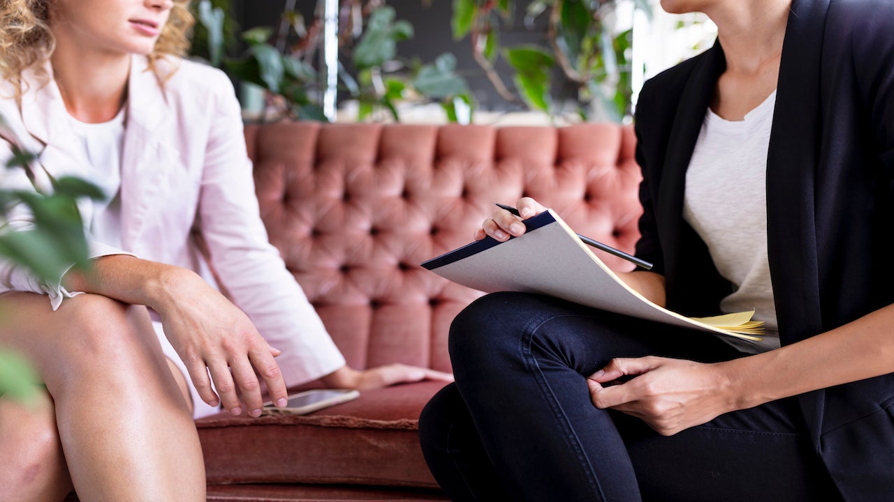 two woman are sitting on a old fashioned sofa
