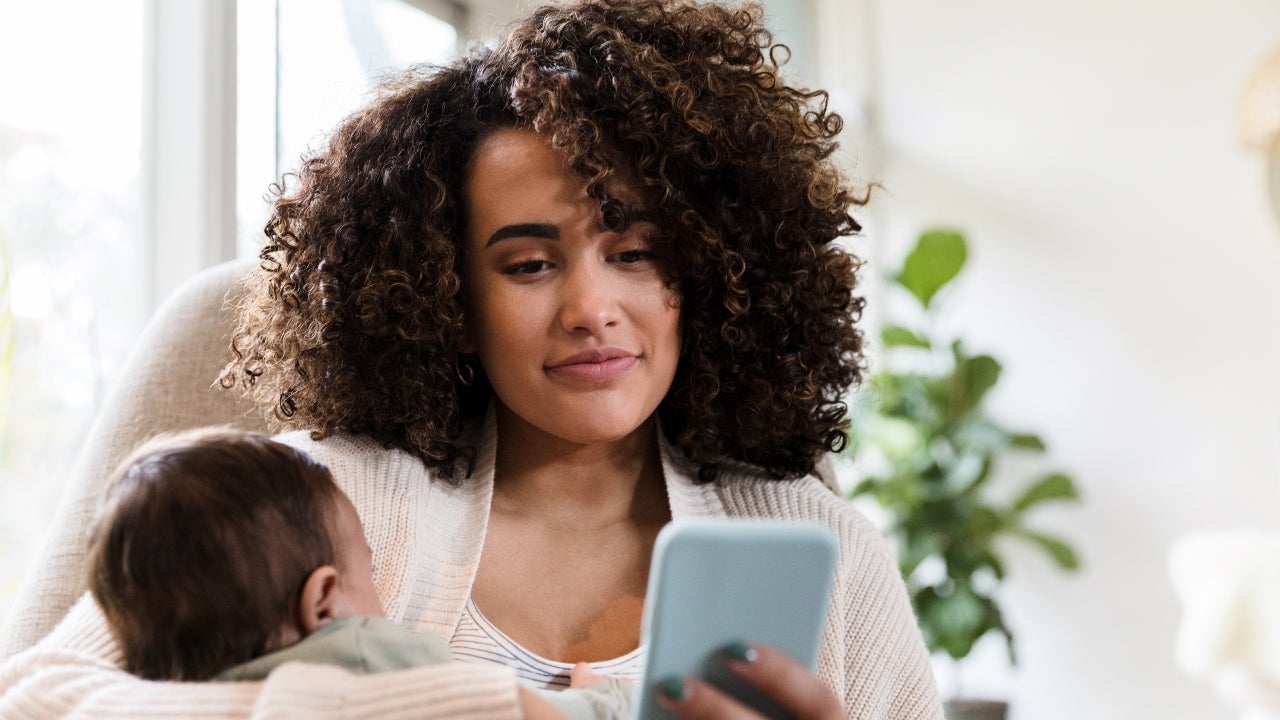 A woman searches for mortgage rates on her phone with her child in tow