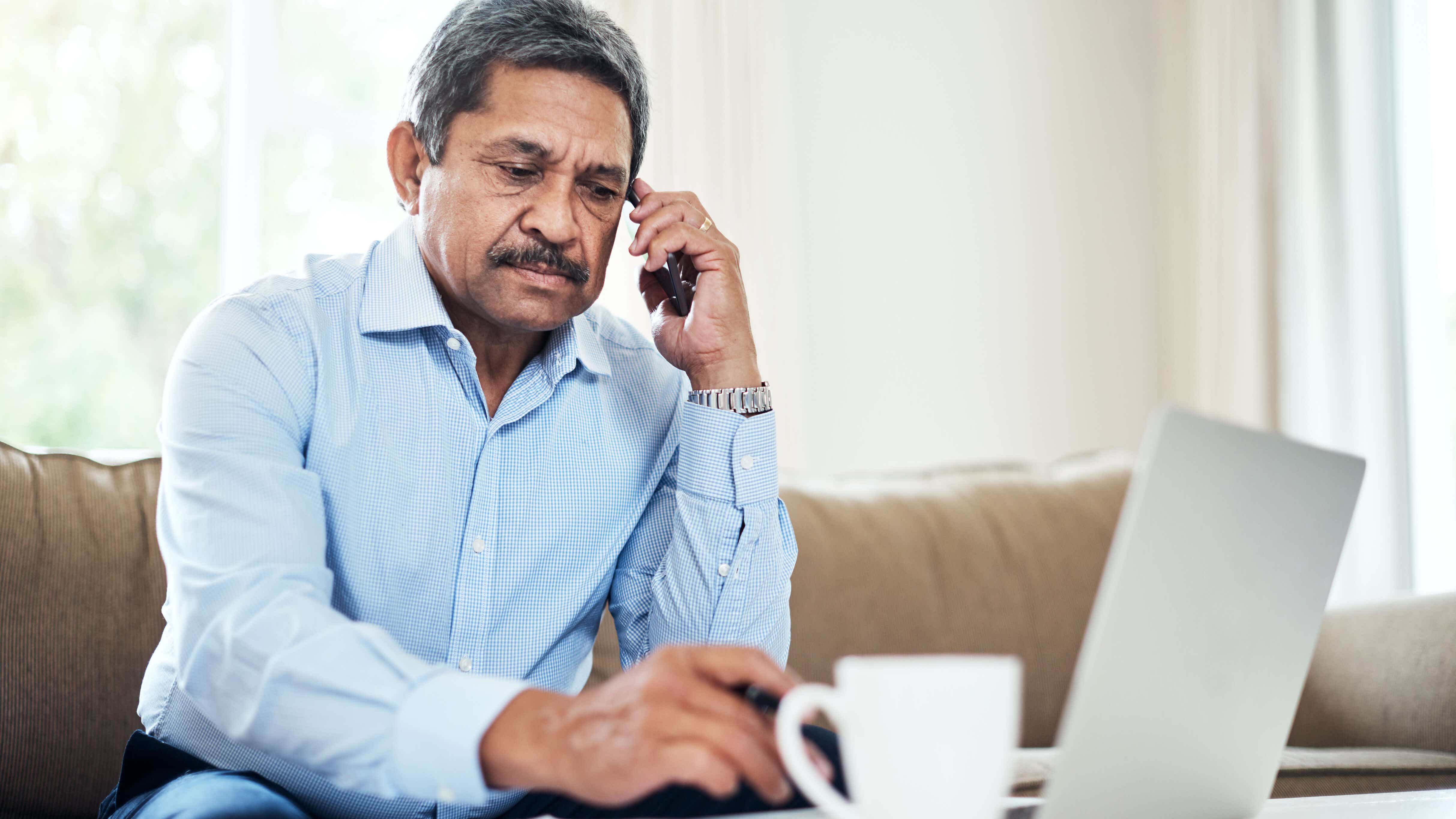 stock image showing a man on the phone at his computer