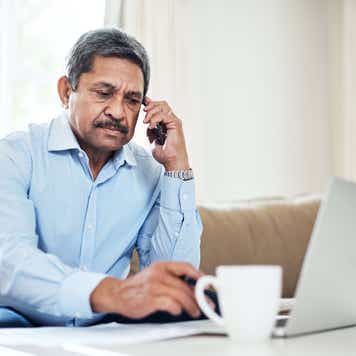 stock image showing a man on the phone at his computer