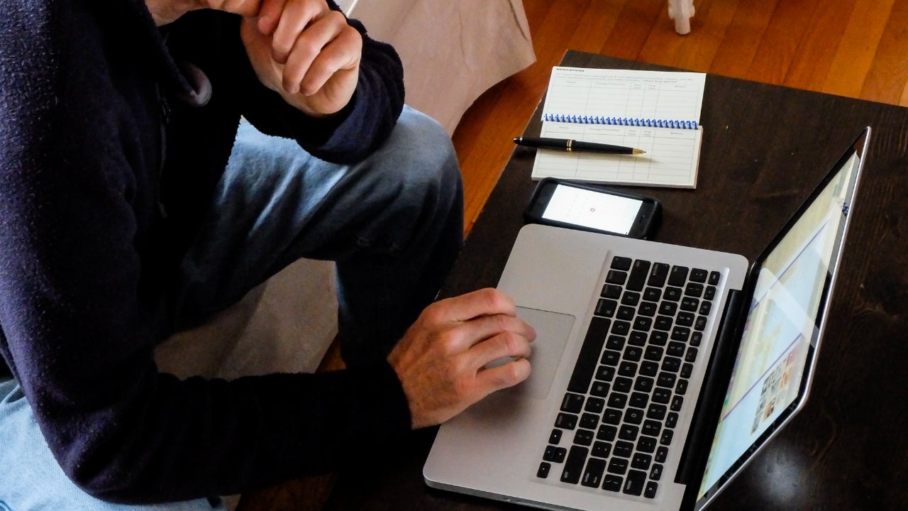 A senior man works on his laptop.
