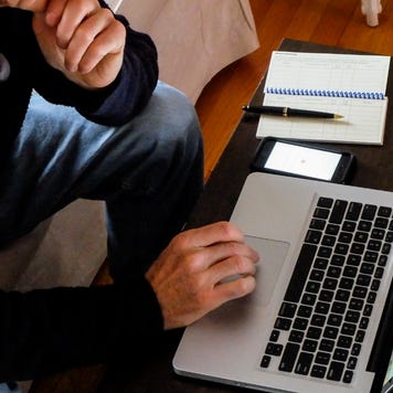 A senior man works on his laptop.