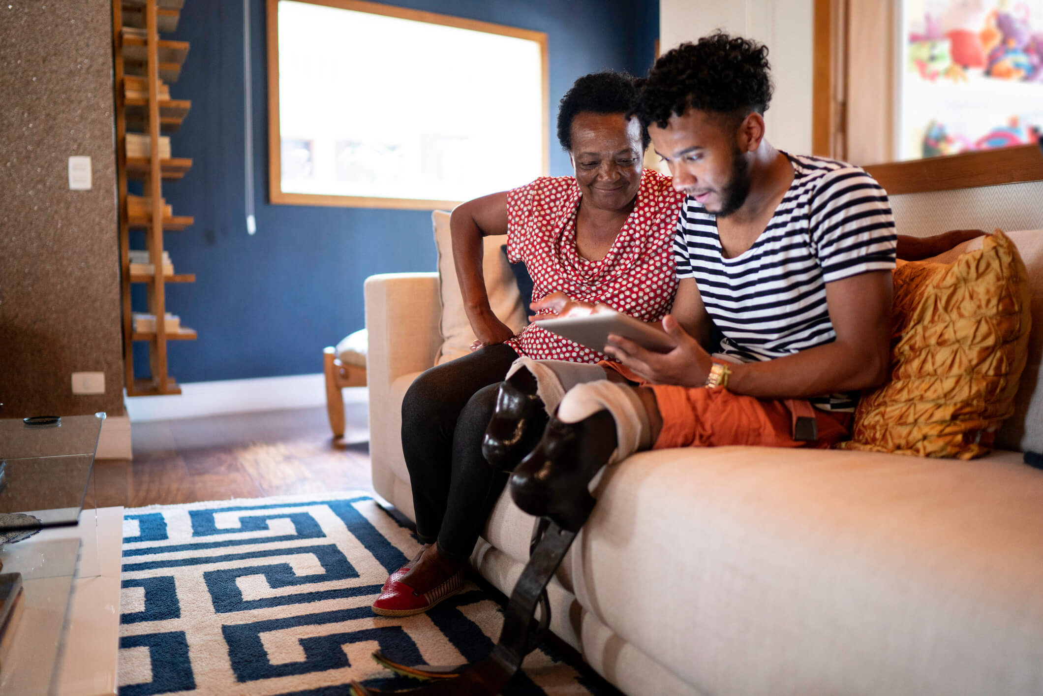 Black, amputee man reviews loan options on a couch.