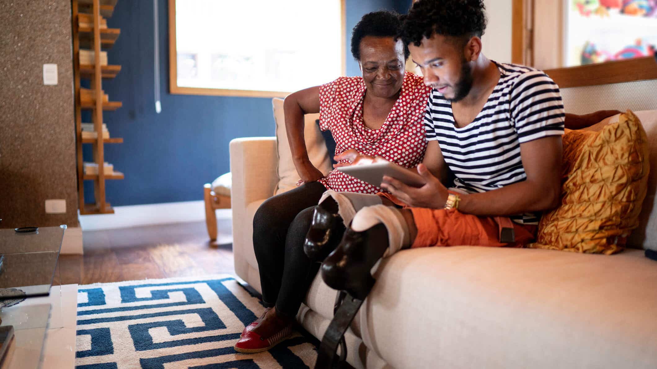 Black, amputee man reviews loan options on a couch.